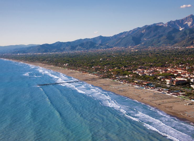 Long range photograph of sea, beach town, and mountains around Forte dei Marmi