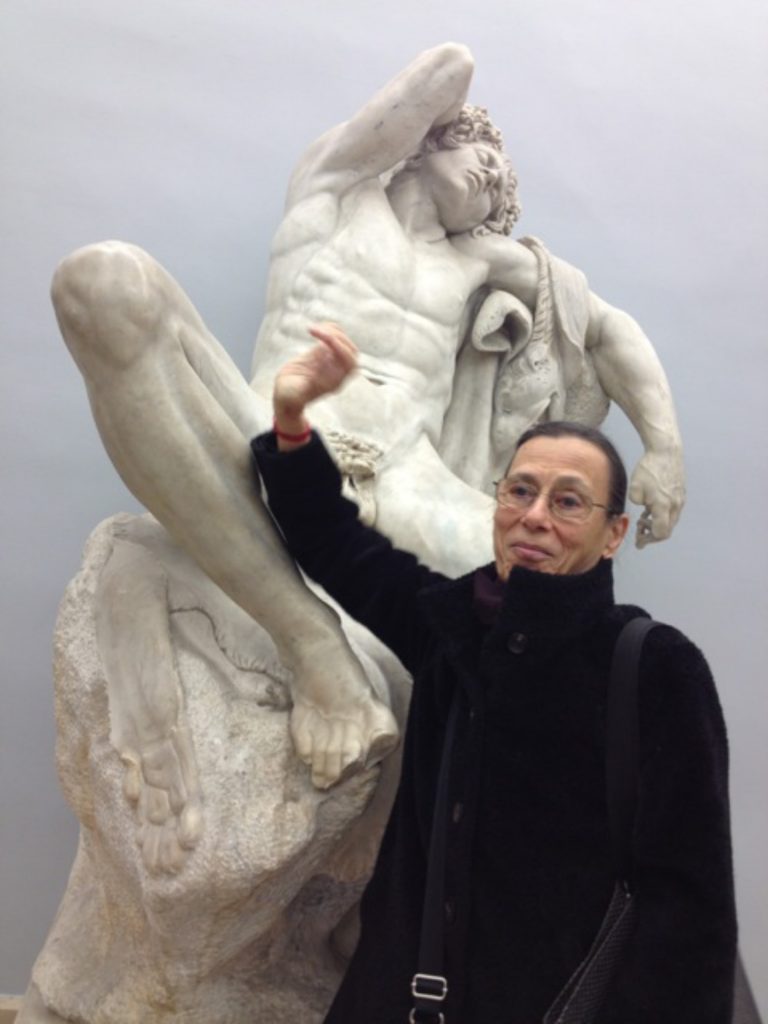 photo of woman holding arm up in front of naked cupid statue